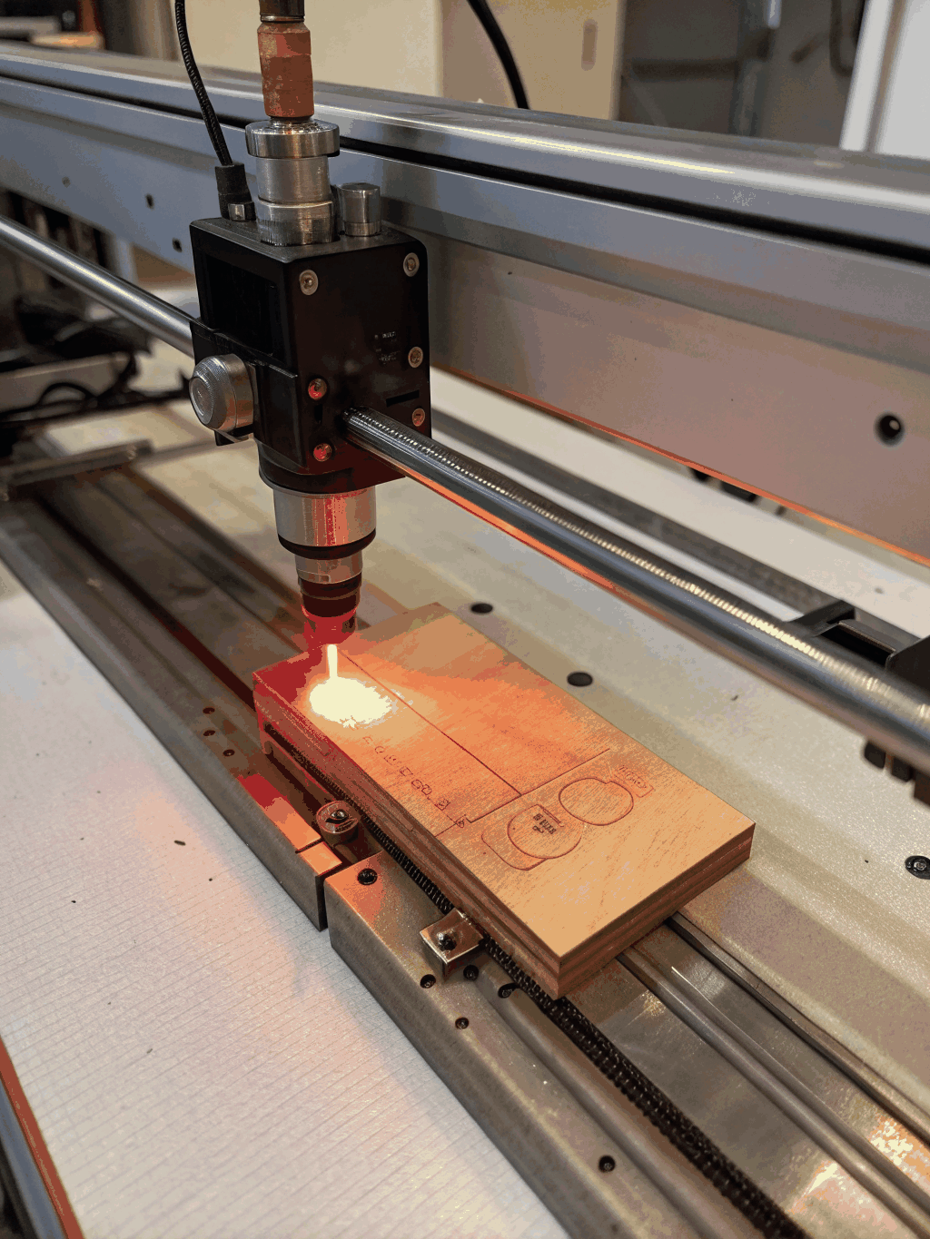 Close up of a CO2 laser head engraving a detailed pattern on wood